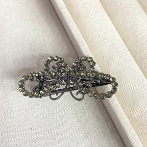 Elegant butterfly hair clip with grey rhinestones on a textured off-white jewelry tray