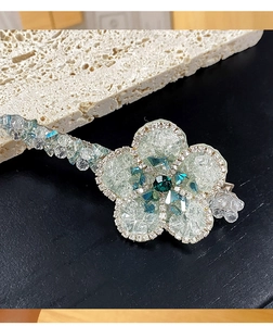 Macro d'une pince à cheveux en forme de fleur avec des pétales en résine et pierre verte