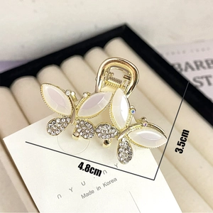 Golden butterfly hair claw with white opal stones and rhinestones for elegant styling