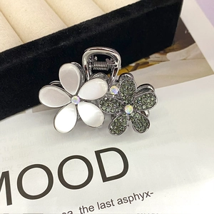 Detail of dual floral hair claw clip with opal effect and green sparkling rhinestones
