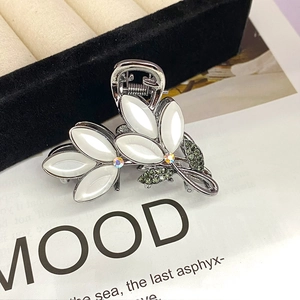Close-up of elegant opal flower hair claw clip with crystal leaf details and metallic finish