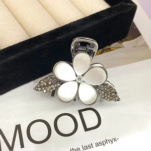 Detailed close-up of opal flower hair claw with sparkling rhinestones and metal leaves
