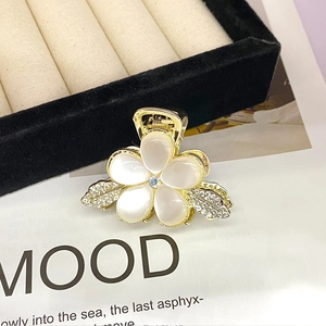 Detail of flower hair claw with white opal petals and sparkling rhinestones on gold base