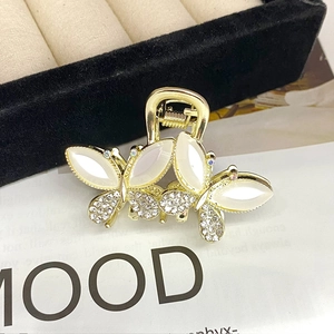 Detailed close-up of golden butterfly hair claw clip with white opal stones and crystals