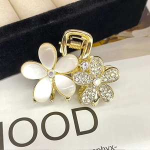 Close-up of golden flower hair claw clip with mother of pearl petals and rhinestones