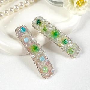 Detail of luxury crystal hair clips with colorful gemstones and floral accents on tray