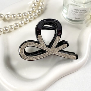 Dettaglio della clip per capelli nera con strass scintillanti su vassoio bianco