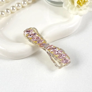 Detailed close-up of crystal bow hair clip with pink stones on a ceramic plate