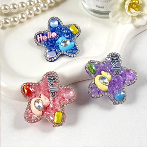 Détail de barrettes en forme d'étoile rose, violette et bleue avec strass étincelants