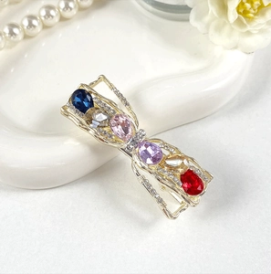 Detailed view of alloy crystal bow hairpin with colorful gemstones on a ceramic plate