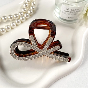 Elegante pinza per capelli grande a tartaruga con strass, mostrata in scena decorativa