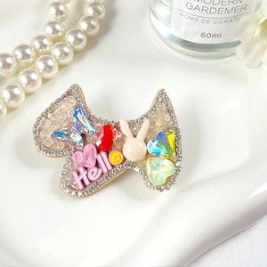 Vue macro détaillée d'une barrette en forme de nœud avec strass colorés et motif Hello