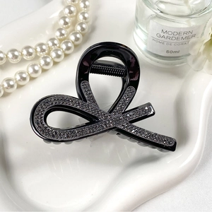Dettaglio macro della molletta per capelli nera con strass su vassoio in ceramica