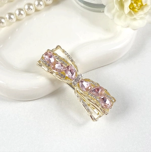 Detail of crystal bow hair clip with pink gemstones on a ceramic tray decoration