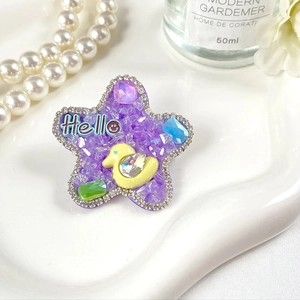 Vue détaillée d'une barrette étoile violette avec strass colorés et un petit canard jaune