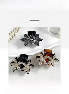 Detailed view of elegant double flower hair claws with rhinestones on a decorative tray