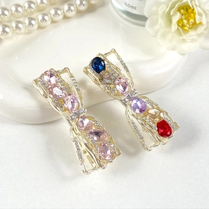 Elegant crystal bow hair clips with colorful rhinestones on a decorative white tray