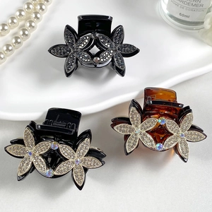 Detailed macro view of three crystal floral hair claws in black and amber resin