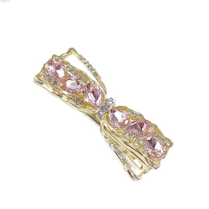 Elegant gold bow hair clip with pink crystal droplets and sparkling rhinestones