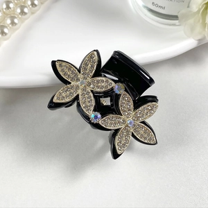 Detail shot of black hair claw clip featuring elegant double floral design with crystal rhinestones