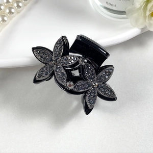 Detailed macro view of black double flower hair claw clip with dark grey rhinestones