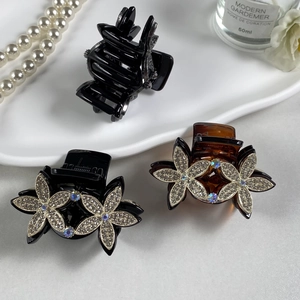 Elegant floral hair claw clips with rhinestones in black and amber on a white tray