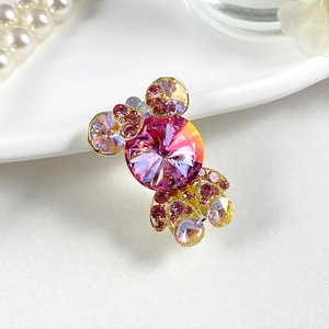 Détail d'une pince à cheveux dorée en forme de bonbon avec cristal rose et strass