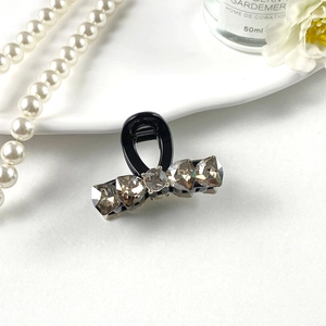 Detail view of mini grey K9 crystal hair claw clip with black resin and small spring teeth