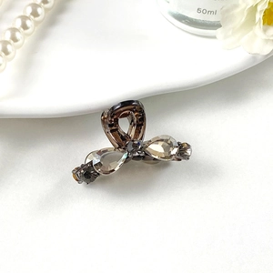 Détail d'une mini pince à cheveux en métal gris foncé avec nœud en strass