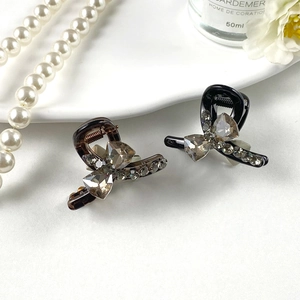 Gray K9 crystal bow hair claw clips in amber and black on an elegant white background