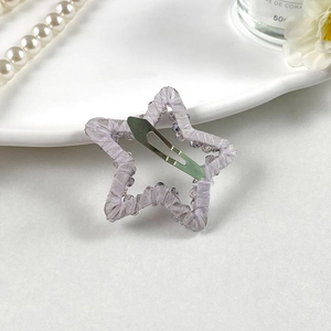 Détail de la pince à cheveux BB en forme d'étoile avec ruban lilas et perles