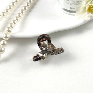 Close-up of a small grey K9 crystal rhinestone bow hair claw with elegant accessories