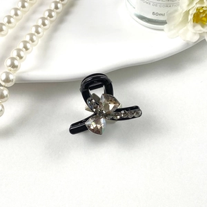 Detailed view of elegant black small hair claw clip with crystal rhinestones on white decor