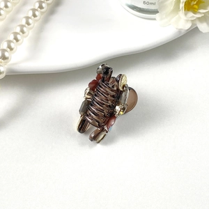 Detail of a brown translucent amber hair claw with rhinestones and metal beads