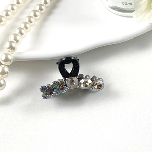Close-up of elegant black hair claw clip with aurora rhinestones and gold flower accents
