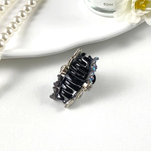 Close-up of a mini hair claw with black resin, grey flower accent and sparkling rhinestones