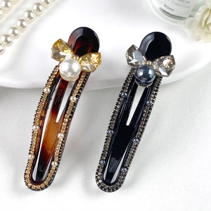 Elegant leopard print hair clips with rhinestones and large pearls on white floral setting
