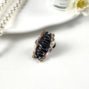 Close-up of mini black hair claw clip with white pearls, pink flowers and crystals