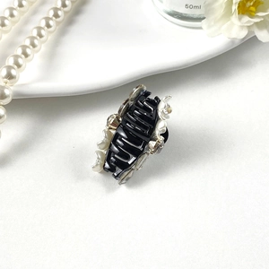 Macro view of elegant black hair claw clip featuring white camellia and pearl details
