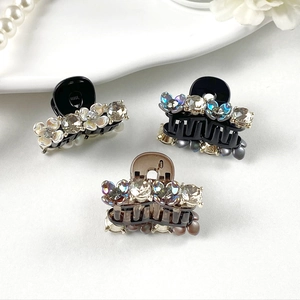 Set of three mini resin hair claws with rhinestones and floral details on a ceramic tray