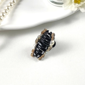Detail of a small French style hair claw clip with pearls and sparkling rhinestones