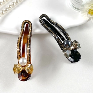 Detail of luxury leopard print hair clips with crystal bows and pearls on white background