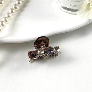 Detail of small hair claw clip with rhinestones and floral accents on resin