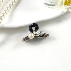 Close-up of elegant black hair claw clip with pearls, crystals and floral details
