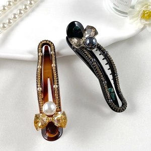 Detailed shot of amber and black hair clips with crystal bows and pearls on tray