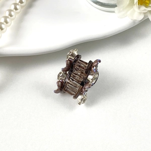 Detail of a mini resin hair claw clip with silver rhinestones and pearls on white background