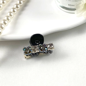 Close-up of a mini hair claw clip with rhinestones on an elegant pearl background