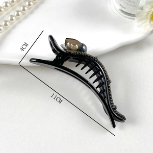 Detail view of 11cm black acrylic hair claw with amber crystal and gold heart accent