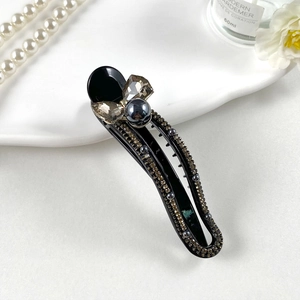 Detail view of a black hair clip with gray faceted crystals and elegant bead embellishments