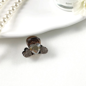 Macro shot of heart-shaped rhinestone hair claw clip with crystal details and brown resin